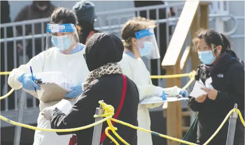  ?? RYAN REMIORZ / THE CANADIAN PRESS ?? People line up for COVID-19 testing in Montreal on Tuesday. About 80 per cent of the more than 2,000 new cases in Canada last week were in Quebec and Ontario where health officials struggle to keep up with demand for testing.