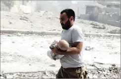  ??  ?? A man carries a baby injured during the air bombardmen­t.