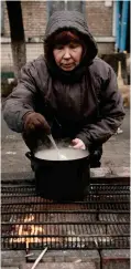  ?? ?? Desperate: A woman cooks outside in Bucha, near Kyiv