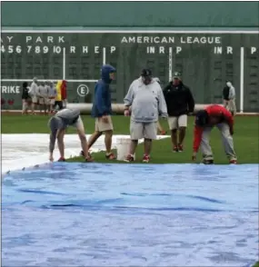  ?? CHARLES KRUPA — THE ASSOCIATED PRESS ?? Grounds crew workers secure a tarp at Fenway Park, Sunday in Boston.