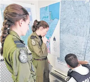  ?? POSTMEDIA NEWS ?? Members of a Royal Canadian Air Force Hercules flight crew looks over a map with an RCMP officer during a manhunt for Kam McLeod and Bryer Schmegelsk­y.