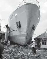  ??  ?? Villagers look at a ship swept ashore.