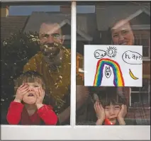  ?? (File Photo/AP/Elizabeth Dalziel) ?? Amelie and sister Camille look out their front window in April as the lockdown enters its third week along with their parents Victoria and Damian Kerr in Berkhamste­d, England.