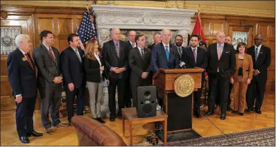  ?? Arkansas Democrat-Gazette/JOHN SYKES JR. ?? Gov. Asa Hutchinson (at lectern) stands with lawmakers Tuesday at the state Capitol after signing a bill to cut the state’s top income-tax rate.
