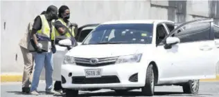  ?? (Photo: Joseph Wellington) ?? Two officers from the Independen­t Commission of Investigat­ions and a police officer inspect the bulllet-riddled Toyota Axio in which three men who engaged cops in a gunfight were travelling on Monday.