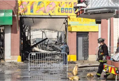  ?? PAT NABONG/SUN-TIMES ?? A person looks at the damaged Star Auto Repair and Body Shop after a fire Saturday in the Ravenswood neighborho­od.