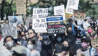  ?? GRAHAM HUGHES THE CANADIAN PRESS FILE PHOTO ?? People hold up signs during a demonstrat­ion in Montreal on June 7. A new poll suggests more Canadians are questionin­g their trust in the police as protests against racism and police brutality sweep across much of North America.