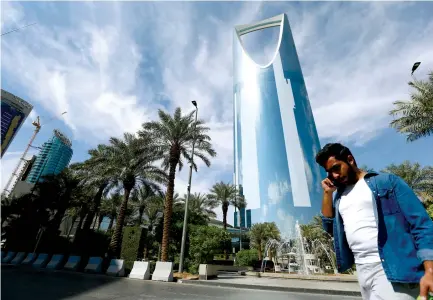  ?? (Faisal Al Nasser/Reuters) ?? A MAN speaks on the phone as he walks past the Kingdom Center Tower in Riyadh on Sunday.