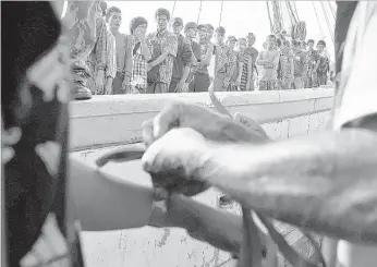  ?? PHOTOS BY DITA ALANGKARA/ASSOCIATED PRESS ?? An Indonesian official put wristbands on rescued Burmese fishermen for identifica­tion purposes upon their arrival Saturday in Tual, Indonesia. The fishermen celebrated their freedom and looked forward to their return to Burma.