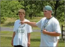  ?? Photo by Steve Sherman ?? Coach Brian Kooser (R) guides the Philadelph­ia Eagles Youth Football Camp, a week-long session held last month at Newtown Friends School. Kooser is a junior offensive tackle at McDaniel College who graduated from CB East.