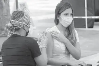  ?? AP PHOTO/MARTA LAVANDIER ?? Maria Oramas gets the first dose of the Pzifer COVID-19 vaccine on Aug. 9, 2021, in Miami. Florida is reporting a surge of COVID-19 cases caused by the highly contagious delta variant.