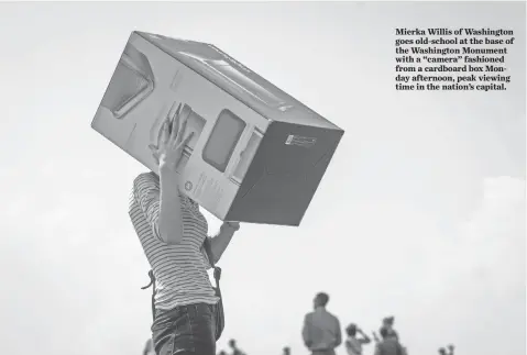  ?? JACK GRUBER, USA TODAY ?? Mierka Willis of Washington goes old-school at the base of the Washington Monument with a “camera” fashioned from a cardboard box Monday afternoon, peak viewing time in the nation’s capital.