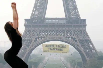  ??  ?? A dancer attends a photo shoot as activists from the environmen­talist group Greenpeace unfurl a giant banner on the Eiffel Tower in a call on French citizens to vote against the Front National presidenti­al candidate Marine Le Pen, below left. Inset...