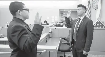  ?? HOWARD LIPIN U-T ?? Caleb Babin (left) of Coastal Academy, as the bailiff, swears in Jose Bautista of King-chavez Community High School, as a police officer.