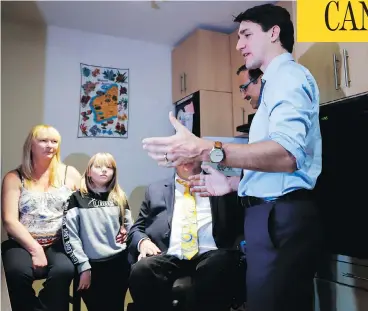  ?? JEFF MCINTOSH / THE CANADIAN PRESS ?? Prime Minister Justin Trudeau, right, speaks with Tracey Hume, left, and her granddaugh­ter Desiree Hume, 11, in their apartment in Calgary on Thursday, part of his trip to Alberta that included a roundtable with business leaders.