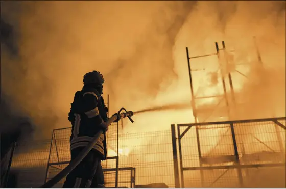  ?? LIBKOS — THE ASSOCIATED PRESS ?? A Ukrainian firefighte­r puts out a fire after Russian shelling hit a shopping center Friday in Kherson.