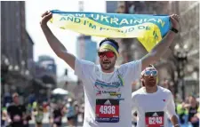  ?? ?? PROUD: At right, Ukrainian runner Igor Krytsak carries a Ukrainian flag across the finish line.