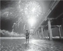  ?? ALLEN J. SCHABEN LOS ANGELES TIMES VIA TNS ?? A person wades into the high-tide surge to get a closer look at the fireworks celebratio­n over the ocean at the pier in Huntington Beach on July 4.