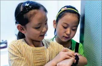  ?? WANG FEI / XINHUA ?? A young visitor (left) takes a photo with her friend using a smart watch with camera and phone functions at the Xinjiang Museum in Urumqi, the Xinjiang Uygur autonomous region. China has become one of the largest markets for kids smart watches, according to official sources.