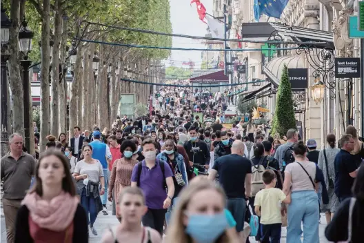  ??  ?? On July 15, 2020, with the summer sales 2020 beginning in France, crowds walk on Champs Elysees, Paris.