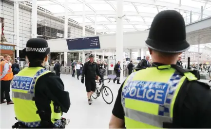  ??  ?? Police watch as commuters arrive at Manchester Victoria railway station on Tuesday in Manchester. (AFP)