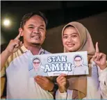  ?? ?? Married couple Hady Irfan (left) and Ajeng Pangesti, K-pop fans and supporters of Anies Baswedan hold campaign merchandis­e made in K-pop style.