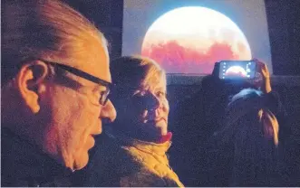  ?? MARLA BROSE/JOURNAL ?? “This has been amazing to watch,” Stephanie Belmore, center, said about the projected image of the super blue blood moon cast from a telescope set up on the Observator­y Deck at the New Mexico Museum of Natural History and Science early Wednesday morning.