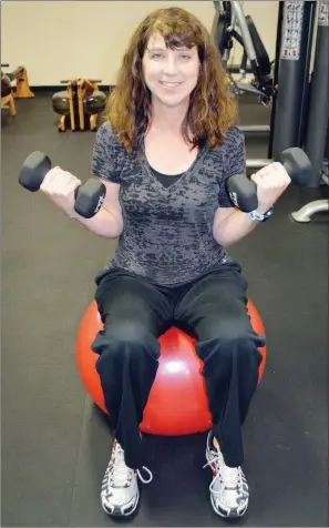  ?? TAMMY KEITH/RIVER VALLEY & OZARK EDITION ?? Sherri Lachowsky, health-and-wellness coordinato­r and personal trainer at the Ola and John Hawks Senior Wellness and Activity Center in Conway, sits on a medicine ball in the facility’s weight room. She teaches several classes for seniors, from Drums Alive to boot camp, and she said studies show social interactio­n and exercise help seniors stay sharper, mentally and physically.