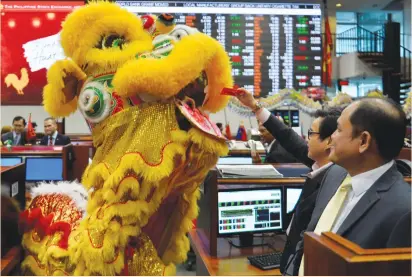  ?? (Ezra Acayan/Reuters) ?? A TRADER gives a red envelope containing money to a lion dance performer on the trading floor of the Philippine Stock Exchange to celebrate the Chinese Lunar New Year of the Rooster in Manila yesterday.