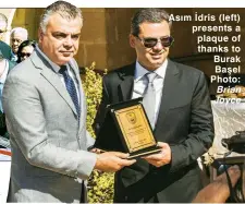  ??  ?? Asım İdris (left) presents a plaque of thanks to Burak Başel Photo: Brian Joyce