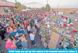  ??  ?? TEXAS: People pray and pay their respects at the makeshift memorial for victims of the shooting that left a total of 22 people dead at the Cielo Vista Mall WalMart (background) in El Paso, Texas. — AFP