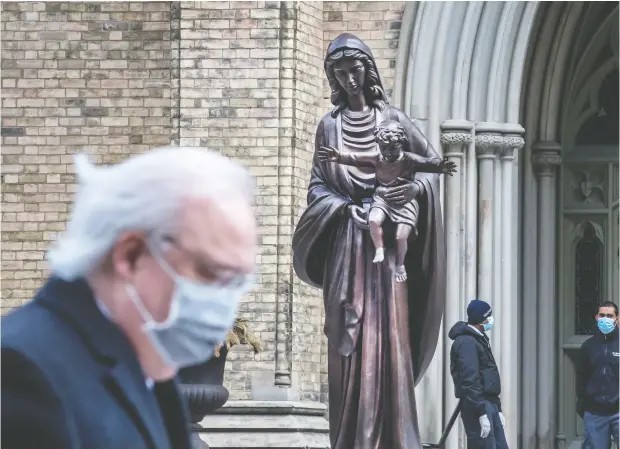  ?? PETER J THOMPSON / NATIONAL POST ?? People near St. Michael’s Cathedral Basilica in Toronto during the pandemic: COVID has not stifled faith, and may even have helped nourish it.
