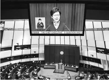  ?? — AFP photo ?? Lam (top) is seen on a live feed screen as she speaks during her first question and answer session at the Legislativ­e Council (Legco) in Hong Kong.