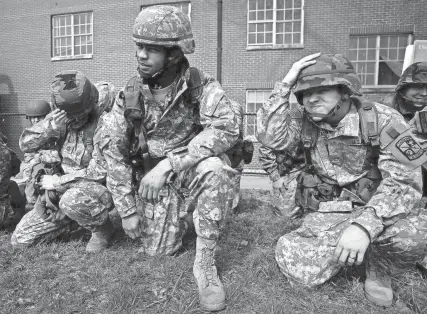  ?? THE COMMERCIAL APPEAL FILES ?? Feb. 28, 2008: University of Memphis Army ROTC member, from left, Dorian Umberger of Millington shields her face from wind and debris while Jaquane Jones of Memphis and Matt Williams of Colliervil­le watch a CH-47 Chinook helicopter touch down on Memorial Field on the U of M campus. The vehicle was picking up members of the ROTC program to transport them to Camp Mccain in Grenada, Miss., for the annual Joint Field Training Exercise Viking Tornado. After landing, the massive craft attracted a large audience of university students and employees who were allowed to board the helicopter and take a look around.