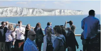  ??  ?? Tourists view the White Cliffs of Dover from a ferry travelling from England to Calais, France.