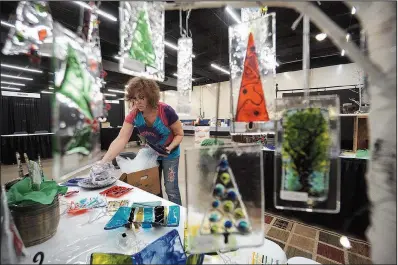  ?? Arkansas Democrat-Gazette/MITCHELL PE MASILUN ?? Katy Remmel of Little Rock sets out her fused glass pieces in preparatio­n for last year’s Arkansas Arts Center Museum School Sale. This year’s sale of locally made artworks will be held this weekend.