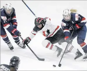  ?? Carlos Osorio Associated Press ?? U.S. FORWARD Hilary Knight (21) and defender Monique Lamoureux (7) reach for the puck next to Canada forward Brianne Jenner in the 2017 world hockey championsh­ips.