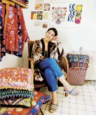  ?? By Jessica Doyle. Photograph­s by Dulcie Wagstaff ?? Above Eleni Malami sits below inspiratio­n pictures and her own artworks, which are transforme­d into colourful cushions. Right Malami at work on a design.