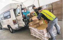  ?? Nick Otto / Special to The Chronicle ?? Daniel Flores and Frank Vickers (in vests) help load gear at the Alameda County emergency services warehouse in Dublin.