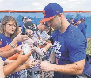  ?? MIKE FITZPATRIC­K/AP ?? Mets outfielder Tim Tebow, set to start the season in Class AAA, signs autographs at spring training.