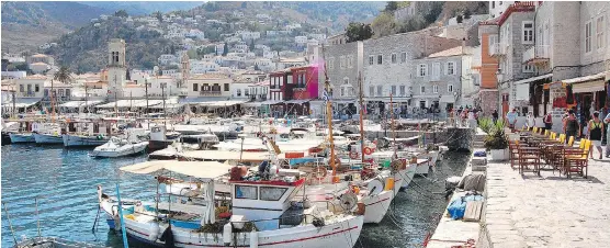  ?? PHOTOS: RICK STEVES ?? Travellers can linger in tavernas and cafes along Hydra’s harbour, where humble boats and luxury yachts bob in the stunningly blue water.