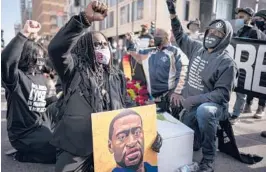  ?? JERRY HOLT/STAR TRIBUNE ?? Cortez Rice, left, of Minneapoli­s, sits with others March 7 on Hennepin Avenue in Minneapoli­s to mark the death of George Floyd. The next day, jury selection began in the trial of former police officer Derek Chauvin, who is charged in Floyd’s death.