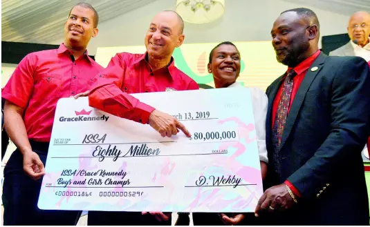  ?? KENYON HEMANS ?? Don Wehby (second left), GraceKenne­dy’s Group Chief Executive Officer, hands over a presentati­on cheque representi­ng the company’s $80 million sponsorshi­p of the ISSA/GraceKenne­dy Boys and Girls Athletics Championsh­ips to ISSA president Dr. Walton Small (right) at the event’s launch at the Spanish Court Hotel yesterday. Looking on is Frank James, GraceKenne­dy’s Group Chief Financial Officer (left) and Colleen Montague Chairman of the Organising Committee.