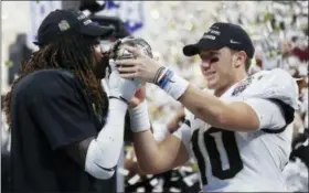  ?? JOHN BAZEMORE — THE ASSOCIATED PRESS ?? Central Florida linebacker Shaquem Griffin, left, kisses the championsh­ip trophy as Central Florida quarterbac­k McKenzie Milton looks on after the Peach Bowl NCAA college football game against Auburn, Monday in Atlanta. Central Florida won 34-27.