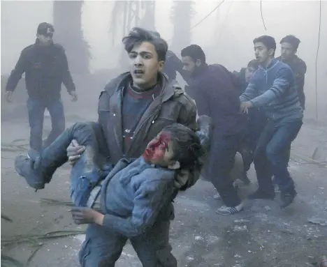  ?? SAMEER AL-DOUMY/AFP/GETTY IMAGES FILES ?? A Syrian carries an injured boy following airstrikes Wednesday on the town of Hamouria, east of the Syrian capital of Damascus.