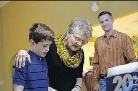  ??  ?? Leslie looks at family photos with her grandson, Davis (left) as her first-born son, Pete, looks on.