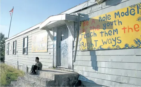  ?? POSTMEDIA NETWORK FILES ?? A boy sits outside the Pikangikum First Nation band office in this file photo. New mental health workers arrived in Pikangikum First Nation on Tuesday to help hundreds of people seeking support in the northern Ontario community.