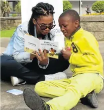  ?? Picture: SUPPLIED. ?? FOR LOVE OF BOOKS: Nal’bali FUNda leader Vuyiseka Ngcawa, left, reads a book while one of the children who joined in the fun activity listens attentivel­y at the pop-up reading session at the East London City Hall last Thursday