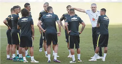  ??  ?? Técnico Tite conversa com seus titulares, já definidos, em treino preparatór­io para jogo contra Argentina