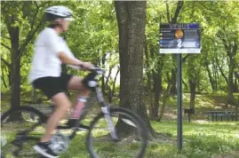  ?? STAFF PHOTO BY ERIN SMITH ?? A biker rides by a sign about the planet Venus on the Chattanoog­a Girls Leadership Academy’s Solar System Walking trail along the Tennessee Riverwalk.